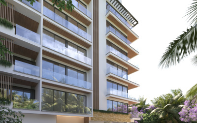 Una imponente fachada moderna de un exclusivo desarrollo inmobiliario, con vista directa al mar Caribe, ubicado en la vibrante Quinta Avenida de Playa del Carmen. La arquitectura combina líneas elegantes y materiales contemporáneos, destacando grandes ventanales que permiten la entrada de luz natural y brindan una conexión fluida con el entorno tropical.